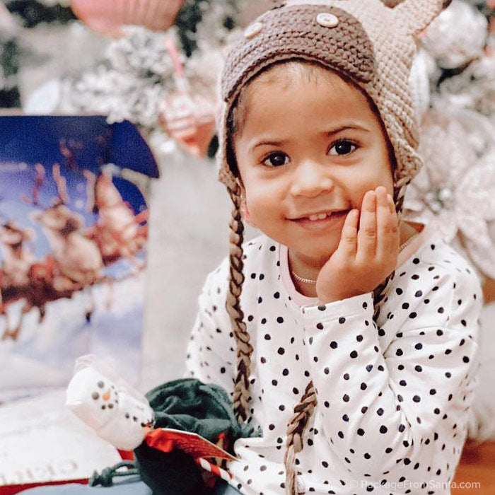 Package From Santa® - little girl wearing her Reindeer Hat and holding a Snowman Marshmallow Pop.