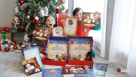 Two children holding up their personalized Santa letters beside two open red Package From Santa boxes with Nice List certificates and keepsakes