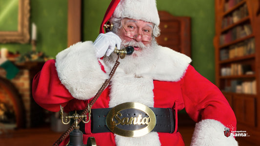 Santa Claus smiling and holding an old-fashioned telephone receiver to his ear in his North Pole study