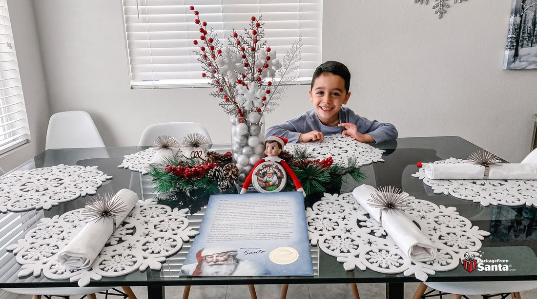 Smiling boy at a decorated table with his personalized letter from Santa and a North Pole elf