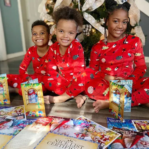 Three smiling children in matching red pajamas with their letters from Santa and Nice List Certificates